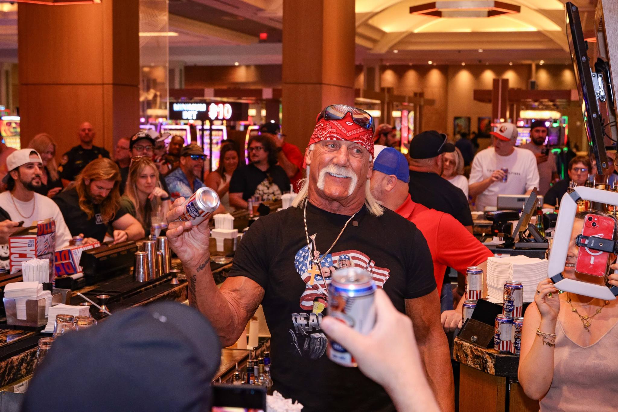 Late WWE legend Hulk Hogan, shown here in 2024 behind the bar of Hard Rock Hotel & Casino - Tampa handing out cans of his Real American Beer.