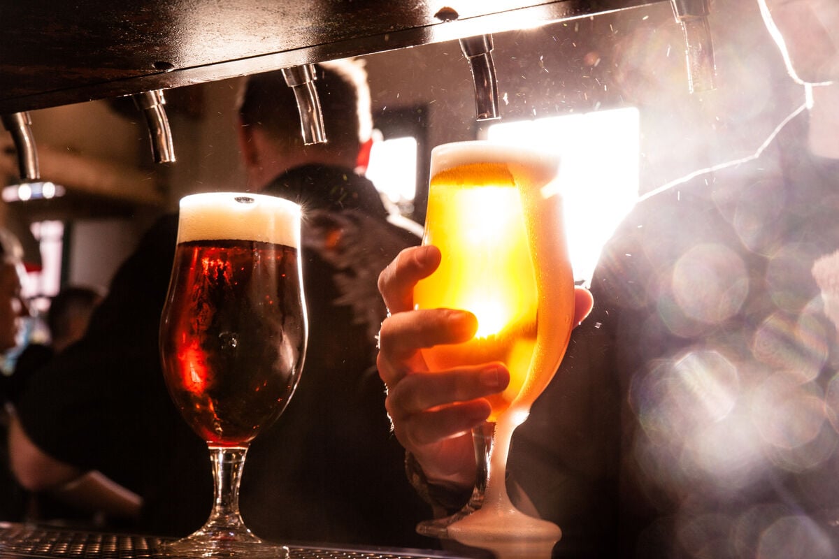 backlit shot of beer glasses under taps