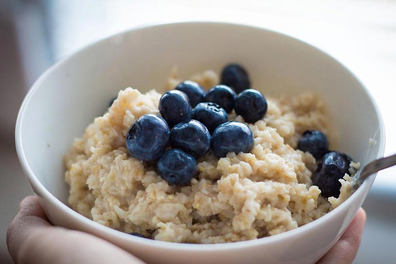 bowl of oatmeal with blueberries on top with a spoon within