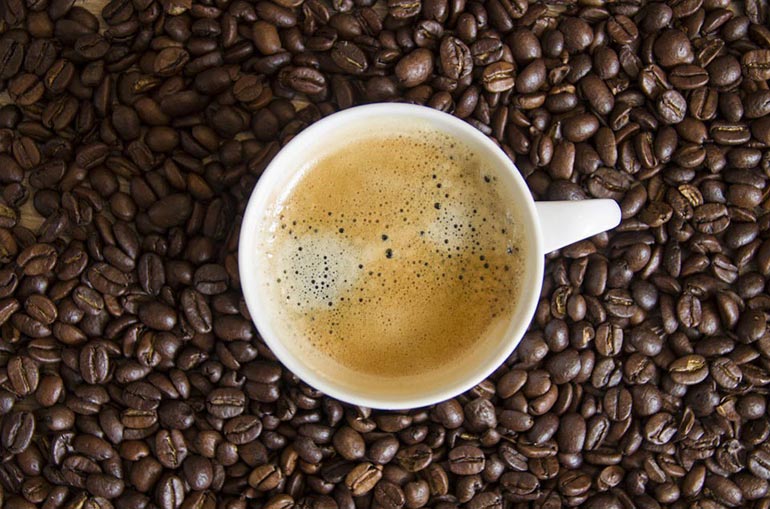 cup of coffee atop coffee beans