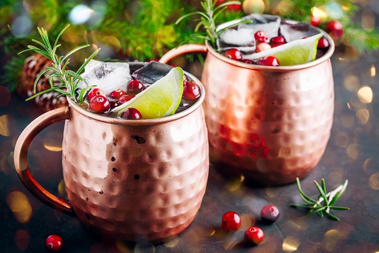 Cranberry Moscow Mule in a copper mug garnished with cranberries and lime.