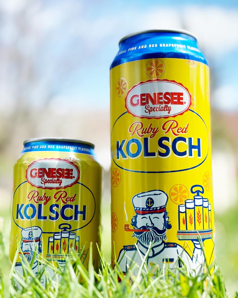 two cans of genesee ruby red kolsch sitting upright on grass