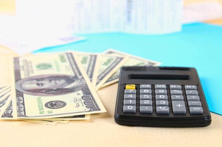 A calculator and USD are placed on a table, symbolizing payday loan calculations