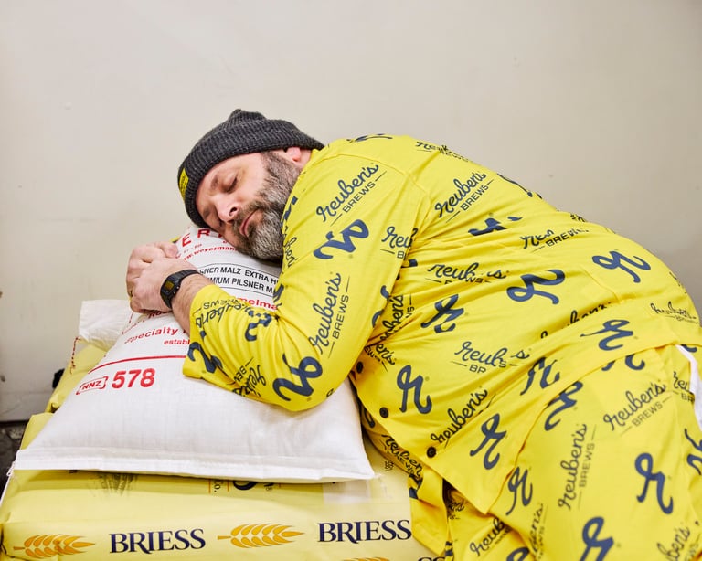 Reuben's Brews Pajama Jammy Jam promotional image of brewer sleeping on grain sack