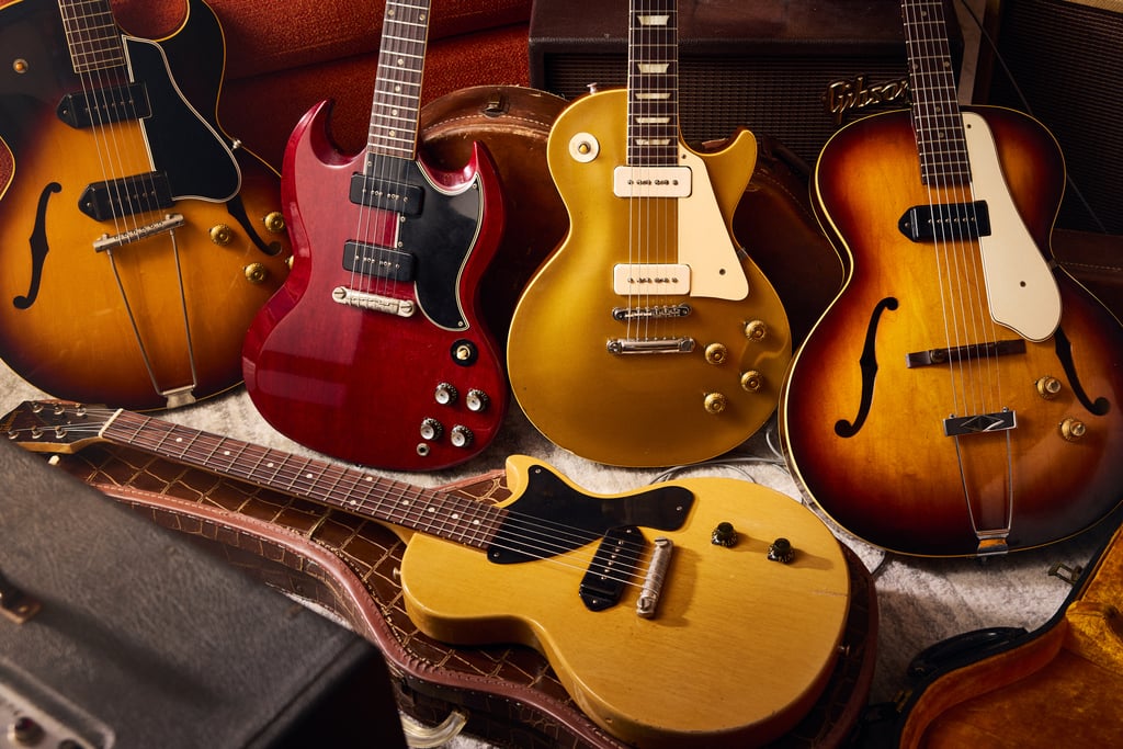 collection of gibson certified vintage guitars in cases and plush sofa
