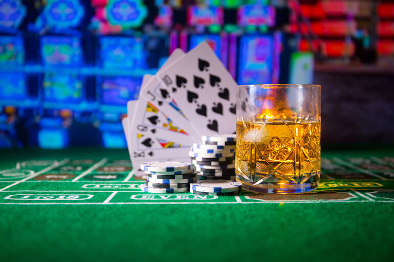 Playing cards, casino chips and an alcohol glass on the table