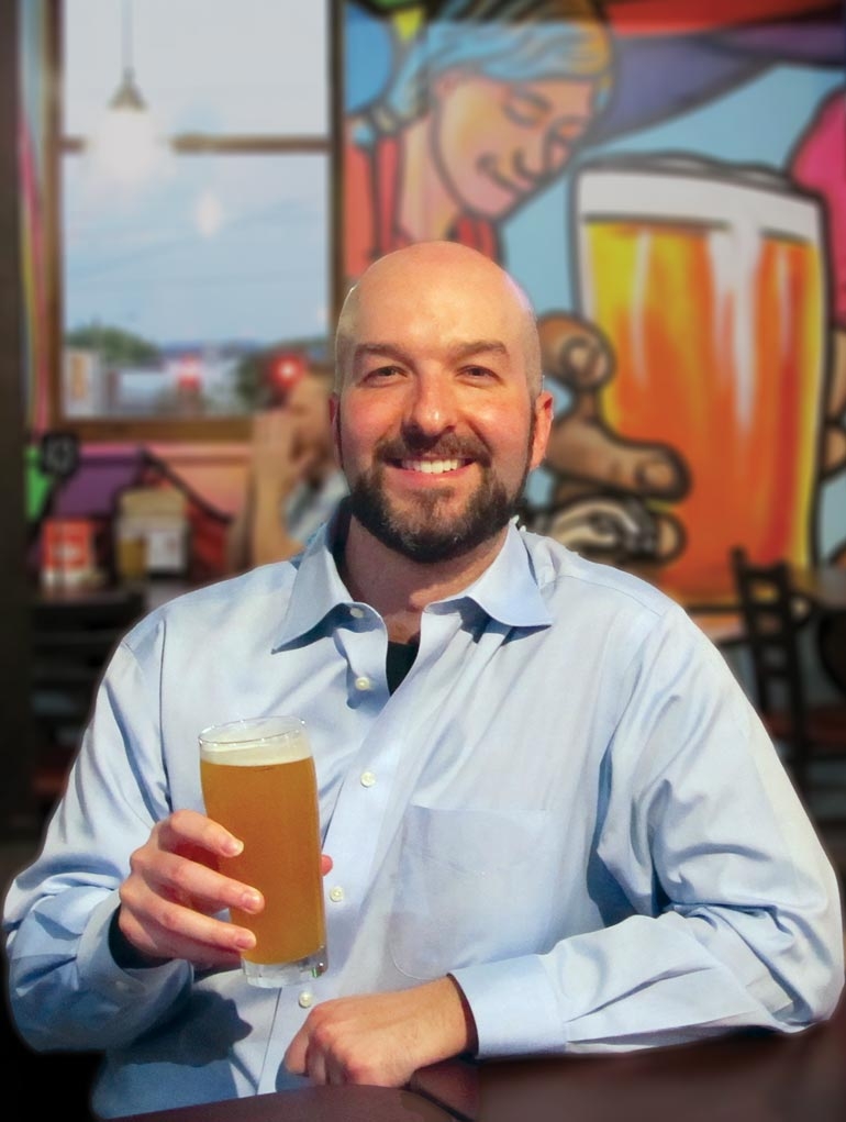Chris Guest holding beer at Tailgate Brewery