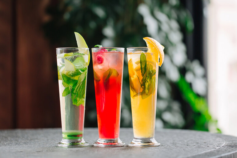 Cold non-alcoholic drinks with apples, oranges, and berries