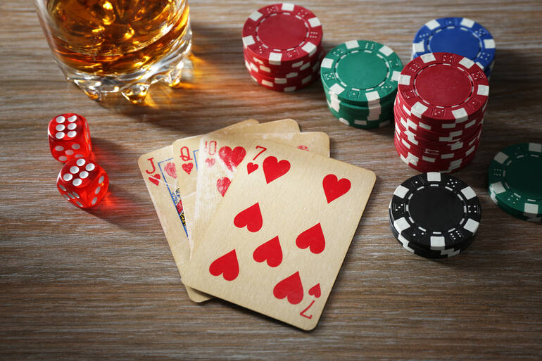 Playing cards, dice, and poker chips with the beer glass on the gambling table