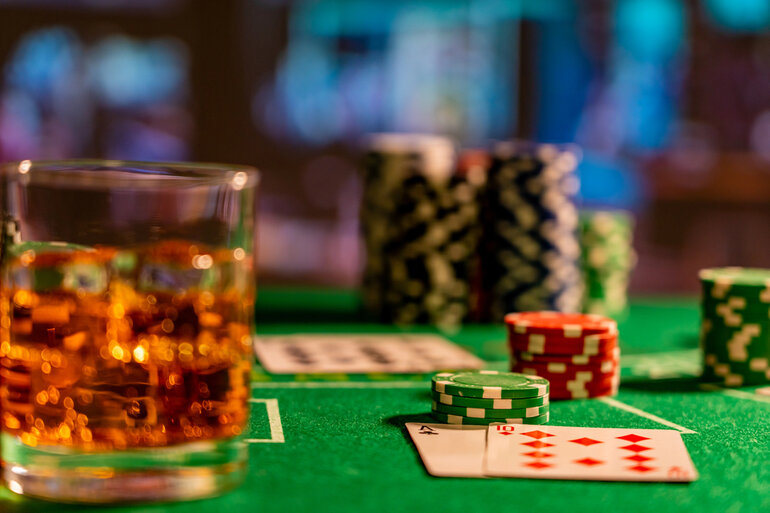 A casino table with a glass of beer, poker chips, and playing cards on it