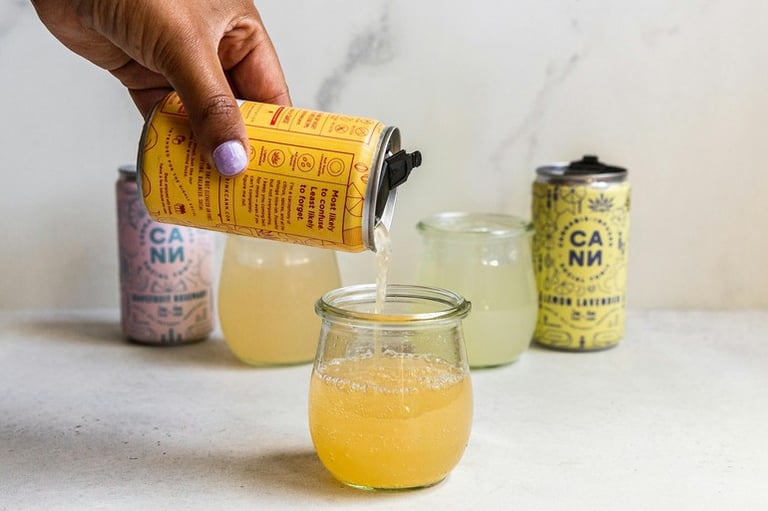 Someone is pouring THC-infused seltzer from a can into a glass jar
