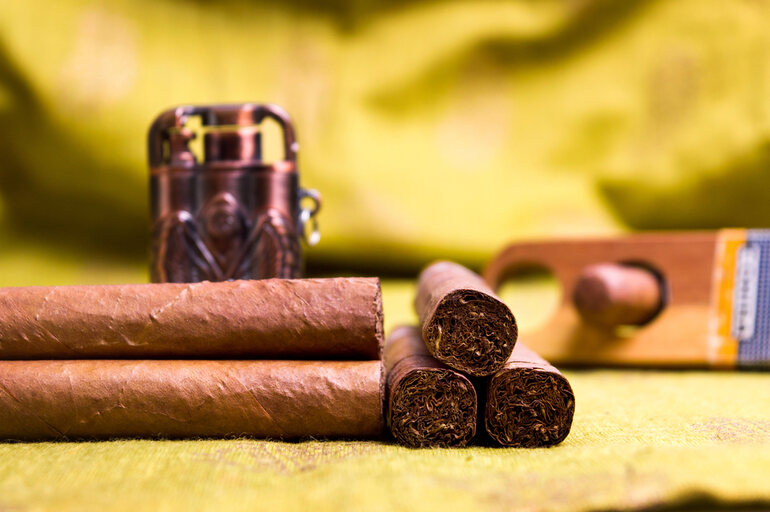 A variety of flavors of cigars on a green surface