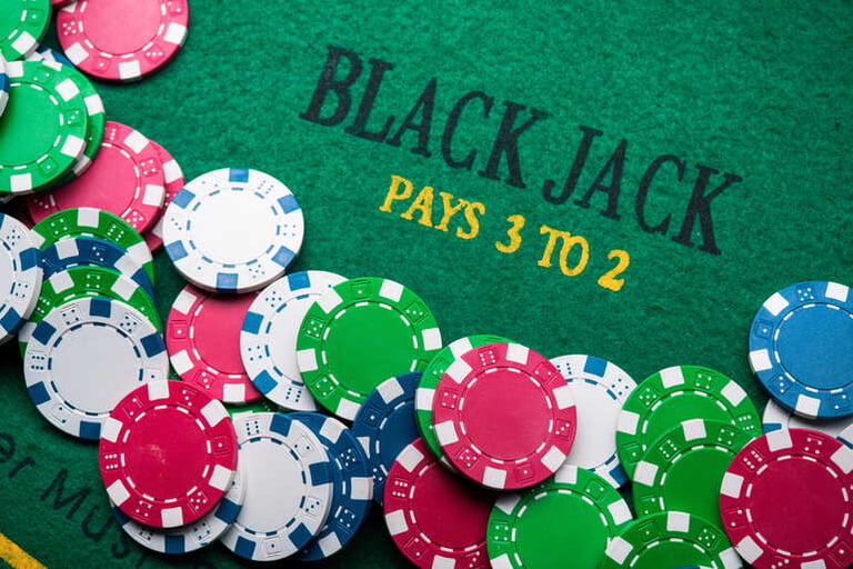 Colorful casino chips are scattered on a blackjack table featuring