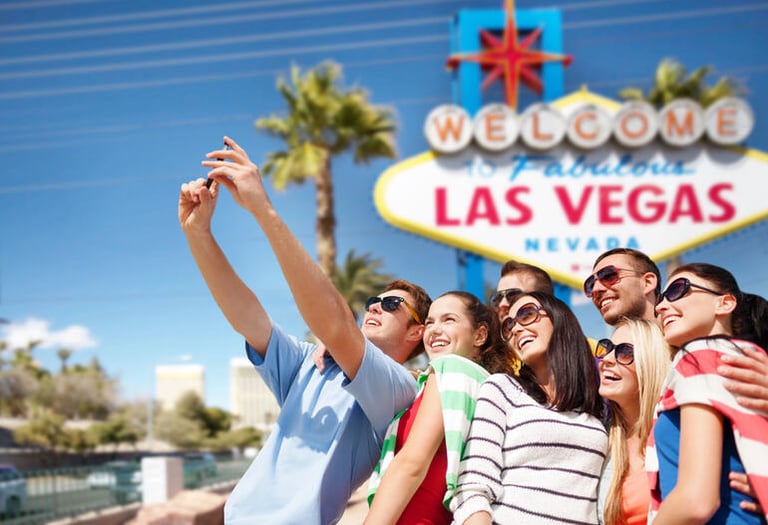 Group of friends taking a selfie in front of the Welcome to Fabulous Las Vegas sign, enjoying live entertainment and leisure in Las Vegas