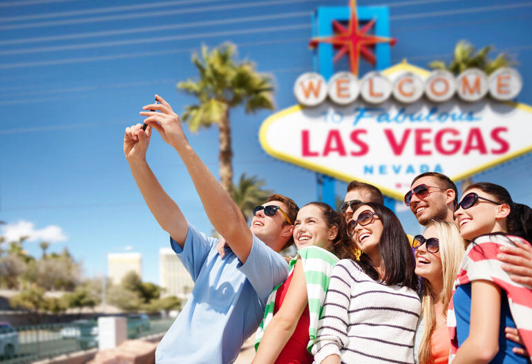 Group of friends taking a selfie in front of the Welcome to Fabulous Las Vegas sign, enjoying live entertainment and leisure in Las Vegas