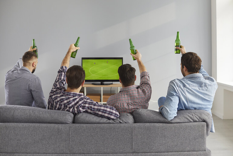 A group of men with beer watching a live football game on TV