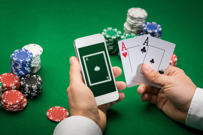 A man is accessing an online casino while sitting in a traditional casino setting