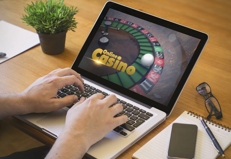 An individual playing online casino roulette on a laptop at home