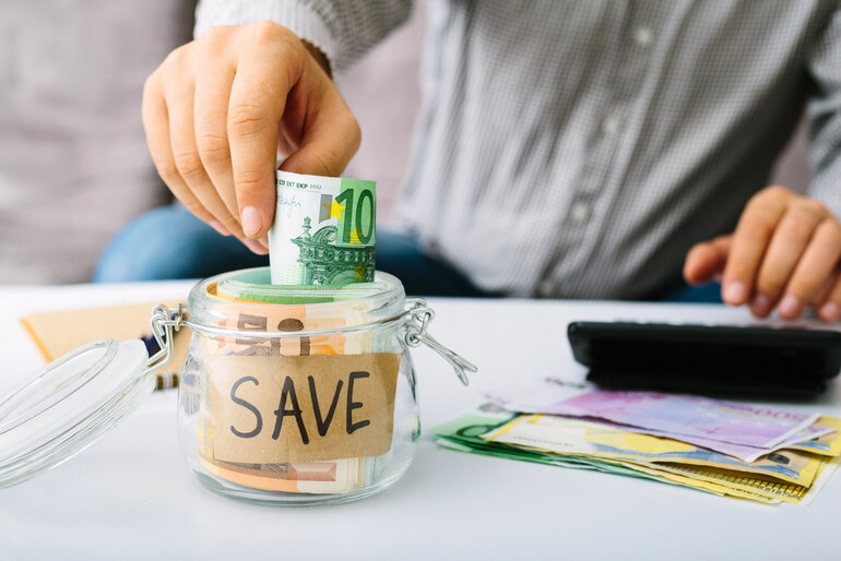 Person saving money in a jar labelled 'SAVE' while calculating expenses, concept of reducing Trulicity costs.