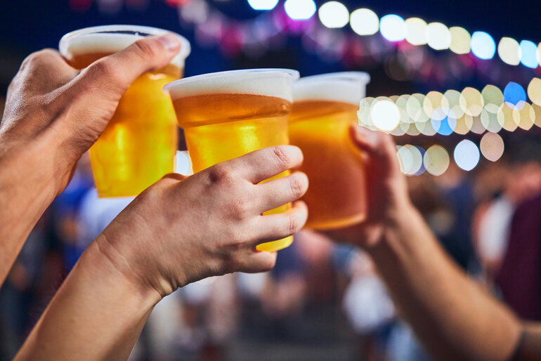 Friends drinking beer at night with defocused lights in the background at a popular US beer festival