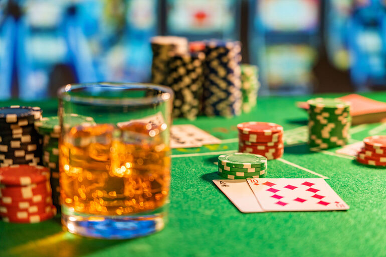Glass of beer on a casino table with poker chips and playing cards