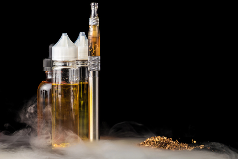 CBD vape cartridges and e-liquid bottles with vapour on a black background