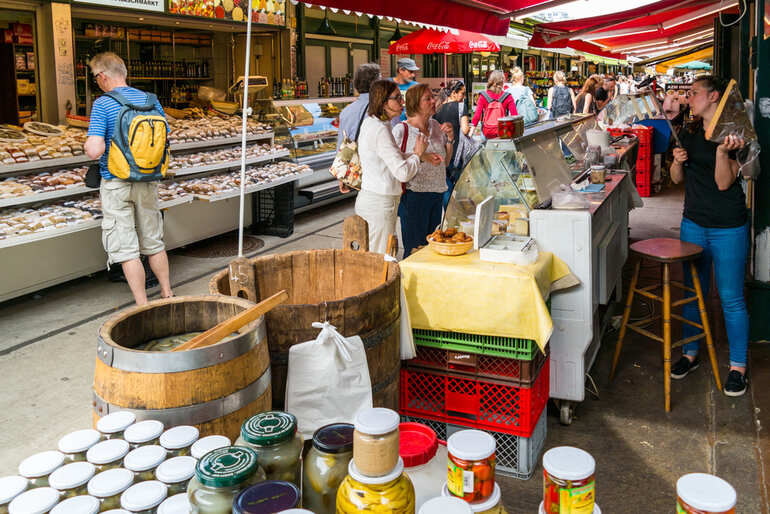 Busy French outdoor market with tourists shopping for local food, preserves, and regional products