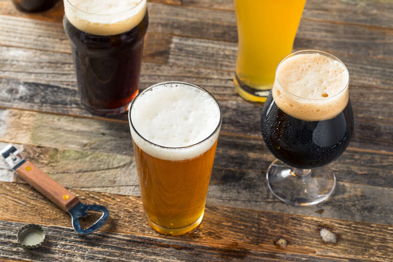 Four glasses of beer, including stouts, IPAs, and wheat ales for sports bettors