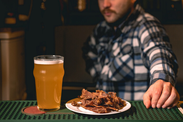 A man is enjoying beer and beef jerky