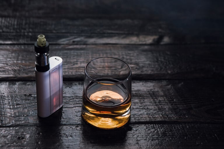 A glass of beer and a vape on the wooden floor