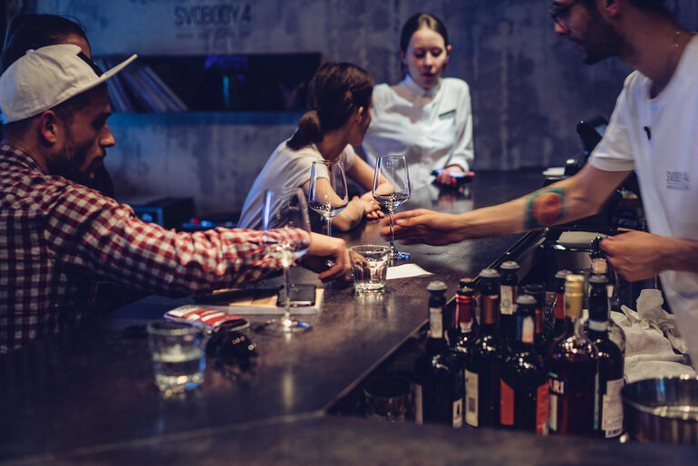 Bartender training in action at a modern bar with professionals practicing drink service and customer interaction