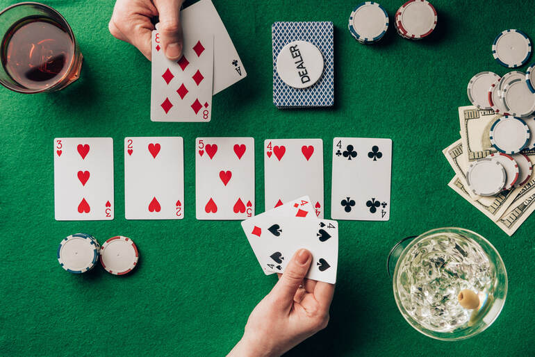 Two players enjoying a home poker game with drinks, chips, and cards on a green felt table during a Friday night gathering