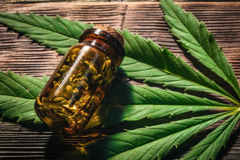 Cannabis essential oil in the vial with a green leaf on a wooden board