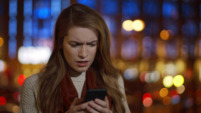 A woman looks disappointed and distracted as her phone displays a notification, controlling her emotions