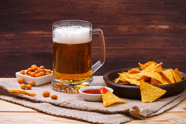 A glass of beer served with tortilla chips, spicy dip, and crunchy snacks for a casual gathering with friends