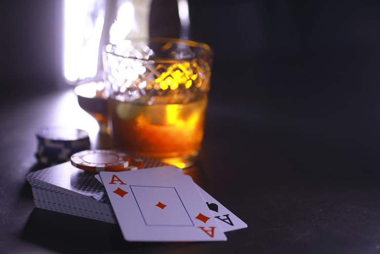 A glass of beer with poker chips and playing cards on a table