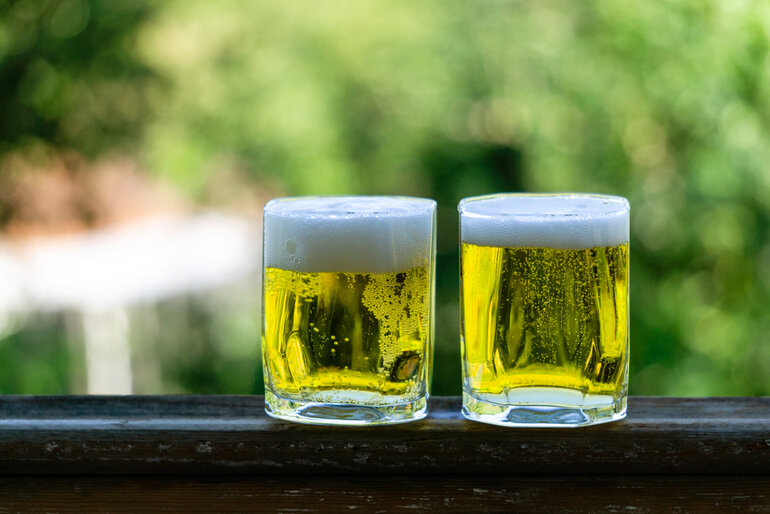 Two glasses of golden pilsner beer with foam, representing a comparison between Czech and German Pilsners