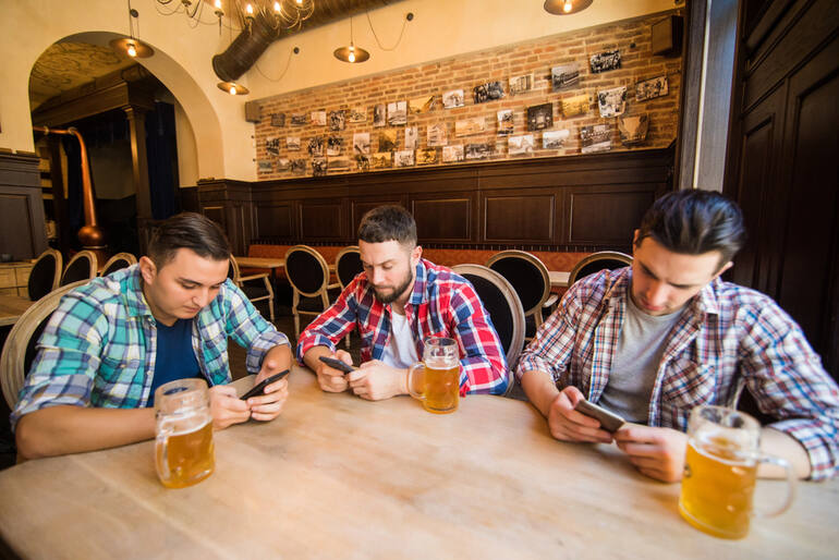 Three young men sitting at a brewpub, who utilized the digital reservation system