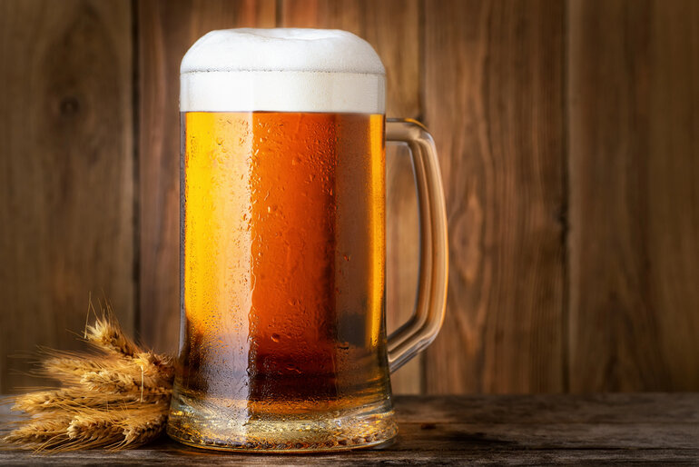 Chilled mug of golden beer with a foamy head on a wooden table