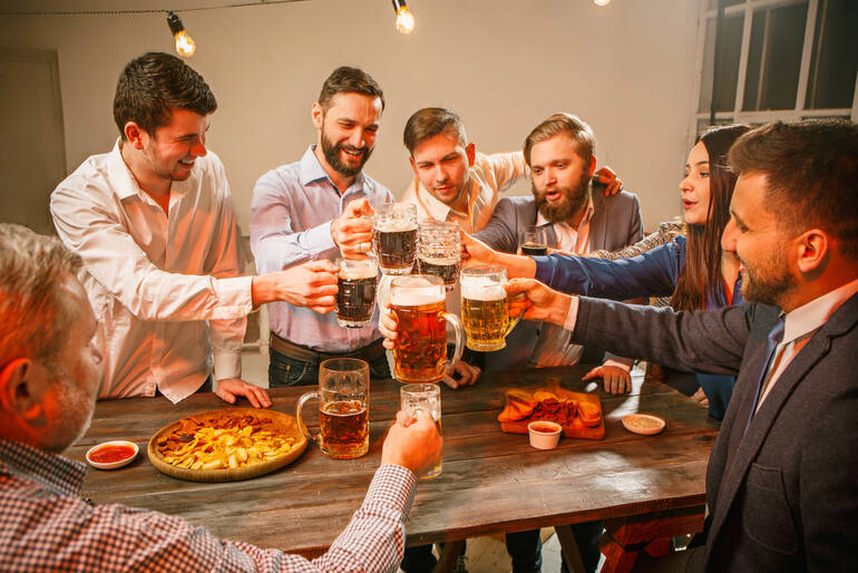 Friends enjoying a beer tasting party with snacks and cheers