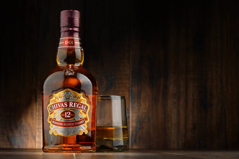 A bottle of Chivas Regal blended Scotch whisky with a glass of whisky beside it
