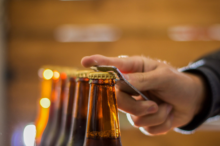 A native american opening a brown beer bottle with a bottle opener
