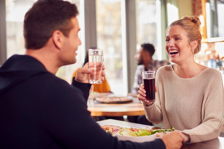 A joyful couple shares laughs and drinks at a cozy restaurant, capturing the excitement and connection of their first beer date after meeting through online dating
