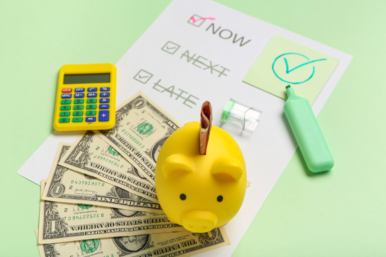 Dollar bills, calculator, and budgeting checklist labeled “Now,” “Next,” and “Late” on a pastel green background