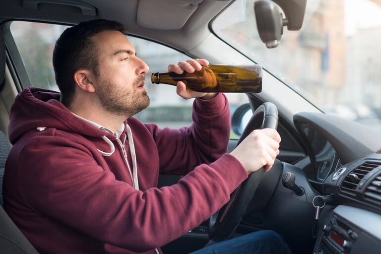 Man drinking beer while driving, representing DUI risk and unsafe driving behavior.