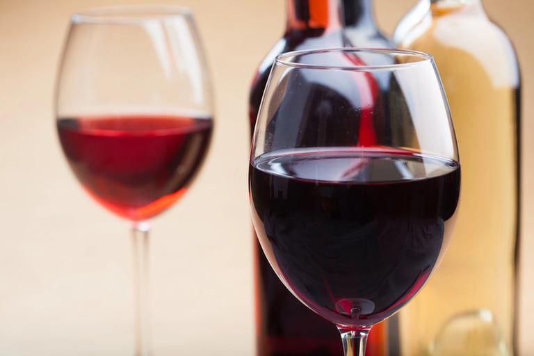 Glasses of red and white wine with bottles in the background