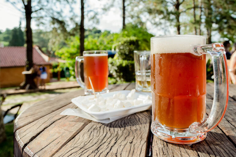 Cold mugs of beer on a wooden outdoor table at a scenic countryside getaway