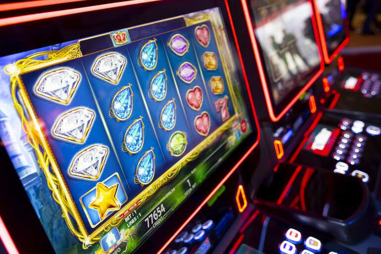 Close-up of modern slot machines displaying colorful animated symbols such as diamonds, stars, and hearts.
