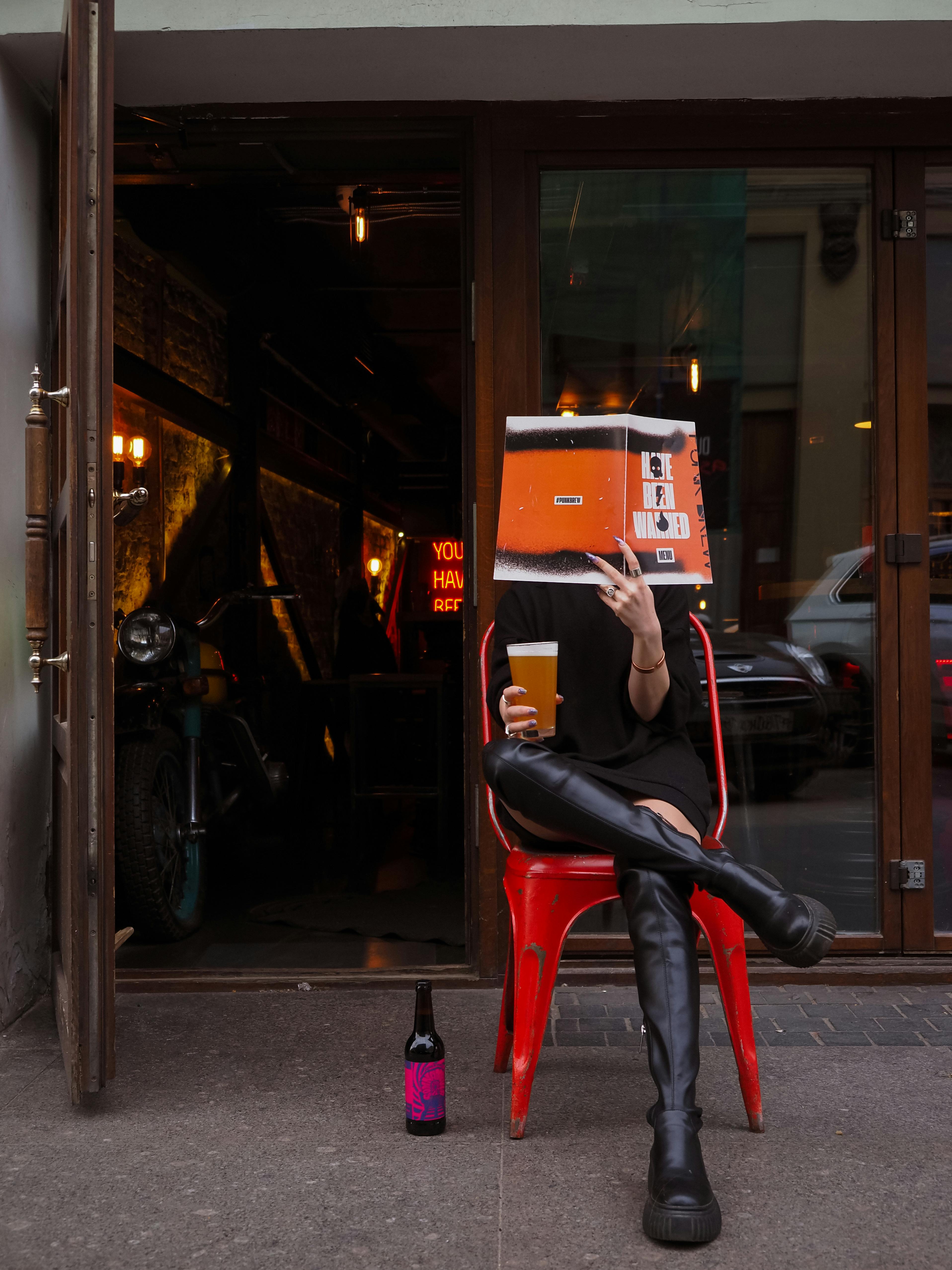 A person with a book on the one hand and a drink one the other in winter attire