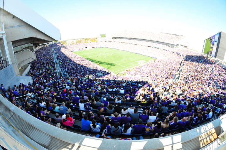 Full stadium crowd wearing purple during a soccer match, study on declining home field advantage since the 1990s.
